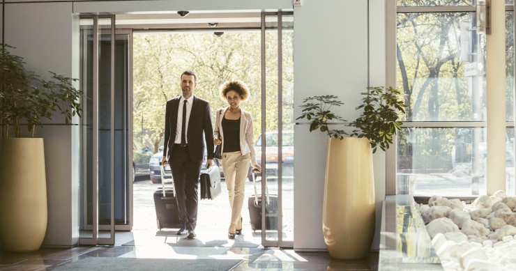Archivo - Viajeros de negocios entrando en un hotel con sus maletas.