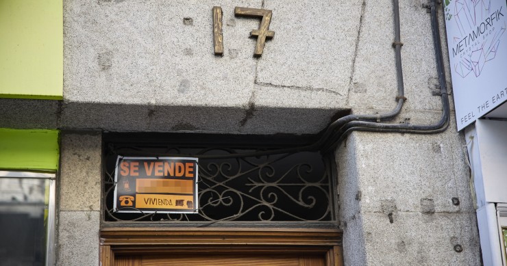 Cartel de una vivienda en venta en el escaparate en el barrio de Almagro