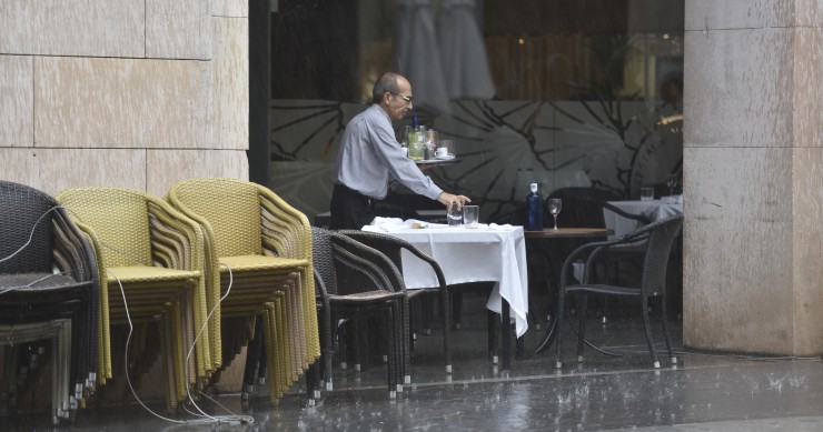 Un camarero recoge una mesa en una terraza