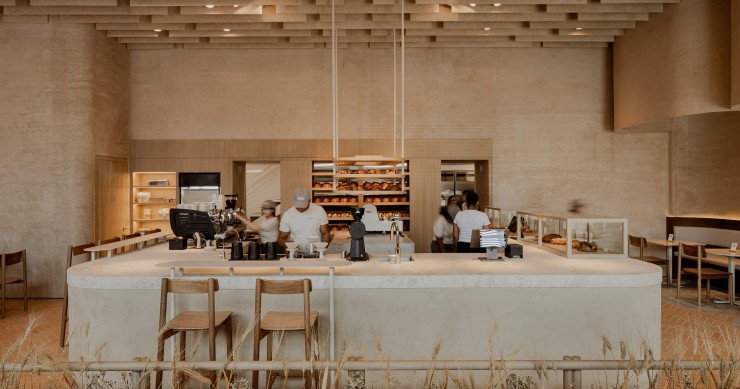 La panadería se articula alrededor de un mostrador en forma de U construido con tierra compactada, una técnica ancestral reinterpretada con elegancia contemporánea.