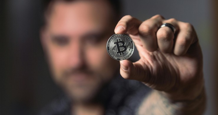 Hombre sosteniendo un bitcoin para comprar vivienda en España