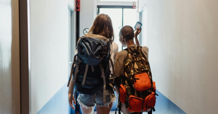 Dos turistas con mochilas entrando en un hotel
