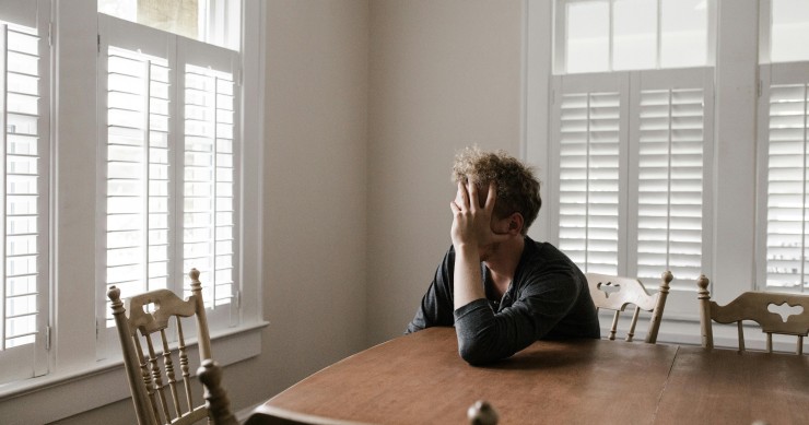 Hombre sentado en la mesa de su casa con gesto triste