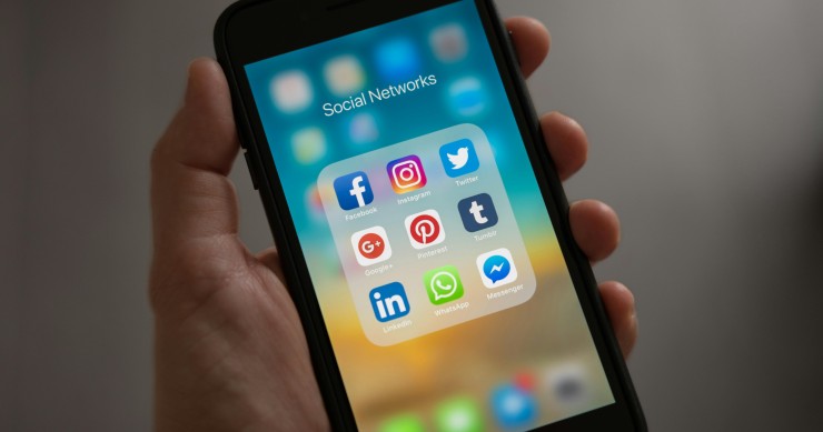 Mano de una autónomo sosteniendo un móvil con aplicaciones de redes sociales