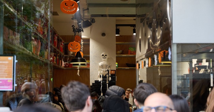 Archivo - Varias personas observan el interior de una tienda en Madrid por Halloween