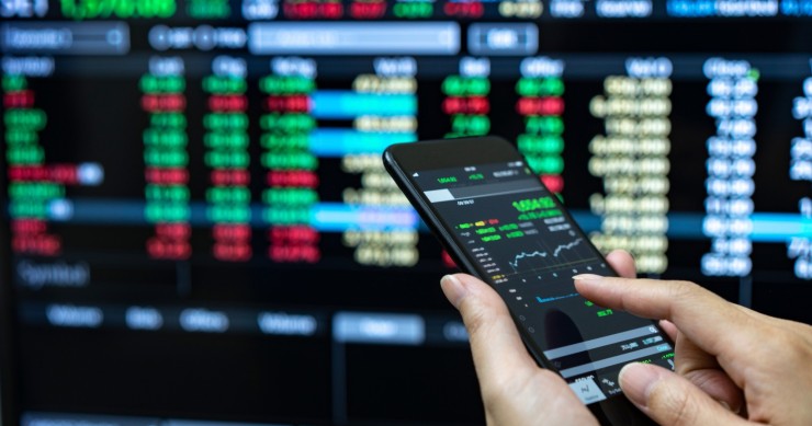 Archivo - Businessman checking stock market data. He using a mobile phone. Analysis economy data on forex earn graph.