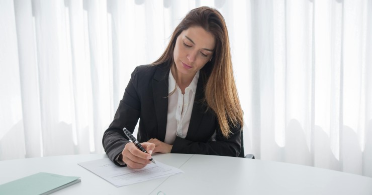 Mujer firmando un contrato privado de compraventa de una cuota hereditaria en una notaría