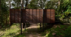 La casa se eleva sobre cuatro esbeltos postes o pilotis, que resuelve el problema del drenaje y crea una sensación de ligereza y conexión con el bosque.