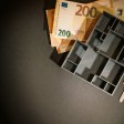 Billetes de euro, una bandeja organizadora y una llave sobre una superficie negra